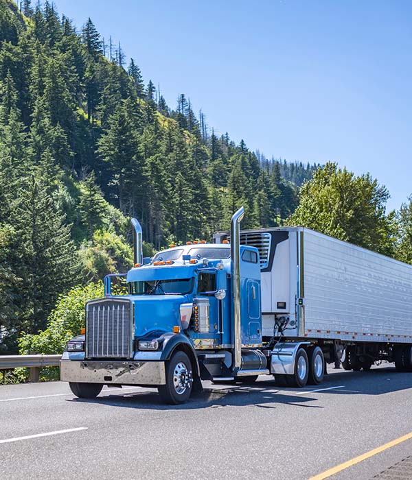 Powerful blue big rig long haul semi truck transporting frozen cargo